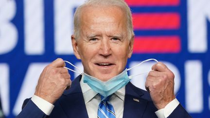 Joe Biden retire son masque avant un discours télévisé, le 4 novembre 2020, à Wilmington (Delaware). (KEVIN LAMARQUE / REUTERS)