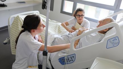 La médecin Anne-Laure Dugenet (à gauche) et l'infirmière Gabrielle Lima (au centre) s'entretiennent avec Michel, un patient de l'hôpital de Vesoul (Haute-Saône), le 23 juin 2023. (YANN THOMPSON / FRANCEINFO)