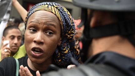 La soeur d'Adama Traoré, Assa Traoré, parle avec un policier lors d'une marche de protestation à la mémoire de son frère, devant la Gare du Nord à Paris, le 30 juillet. (DOMINIQUE FAGET / AFP)