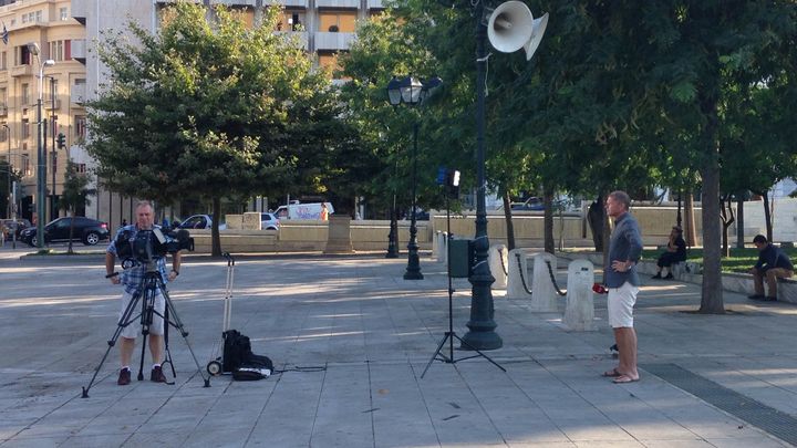 Un journaliste attend avant de faire un direct t&eacute;l&eacute;vis&eacute;, place Syntagma &agrave; Ath&egrave;nes (Gr&egrave;ce), le 15 juillet 2015. (ARIANE NICOLAS / FRANCETV INFO)