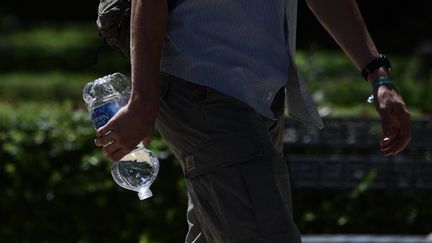 Un passant porte une bouteille d'eau à Séville en Espagne le 16 juillet 2023. (CRISTINA QUICLER / AFP)