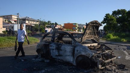 Une voiture brûlée dans une rue de Fort-de-France, en Martinique, le 23 septembre 2024. (ED JONES / AFP)