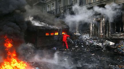 Un manifestant lance un pneu dans le feu &agrave; Kiev, le 23 janvier 2014. (SERGEI GRITS / AP / SIPA)