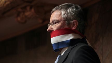 Nicolas Dupont-Aignan se baîllonne à l'Assemblée nationale pour protester contre les règles de prises de parole dans l'hémicycle, le 12 juillet 2011. (JACQUES DEMARTHON / AFP)