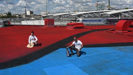 Les street artists Ella (G) &amp; Pitr (D) sur le toit d'un pavillon de Paris Expo, Porte de Versailles à Paris, réalisent la plus grande fresque d'art urbain d'Europe en juin 2019. (DOMINIQUE FAGET / AFP)