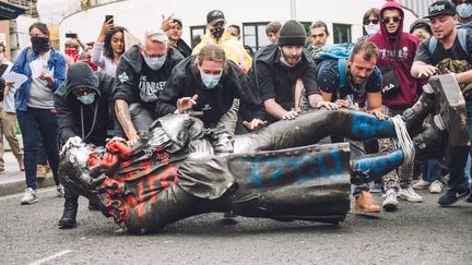 Des manifestants traînent la statue d'Edward Colston vers la rivière Avon à Bristol, dans l'ouest de l'Angleterre. Edward Colston (1636-1721), qui fut marchand d'esclaves, a joué un rôle important dans le développement de la ville.&nbsp; (AFP - GIULIA SPADAFORA / NURPHOTO)