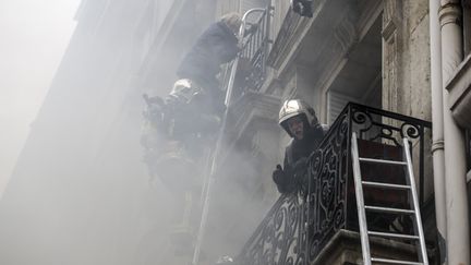 Un riverain est évacué par les pompiers après l'explosion d'une boulangerie au coin de la rue Sainte-Cécile et de la rue de Trévise, samedi 12 janvier, peu avant 9h du matin.&nbsp; (THOMAS SAMSON / AFP)