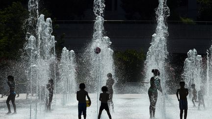 Des enfants se rafraîchissent durant un épisode de canicule dans une fontaine du parc André Citroën, à Paris, le 26 juillet 2018. (ALAIN JOCARD / AFP)