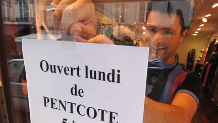 Un commerçant pose une pancarte sur sa vitrine -avec une faute d'orthographe à "Pentecôte"- le 2 juin 2006, à Caen (Calvados). (MYCHELE DANIAU / AFP)