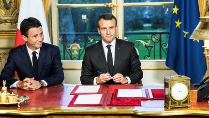 Le président de la République, Emmanuel Macron, signe trois textes de loi, le 30 décembre 2017, à l'Elysée, à Paris, aux côtés de Benjamin Griveaux, porte-parole du gouvernement. (ETIENNE LAURENT / AFP)