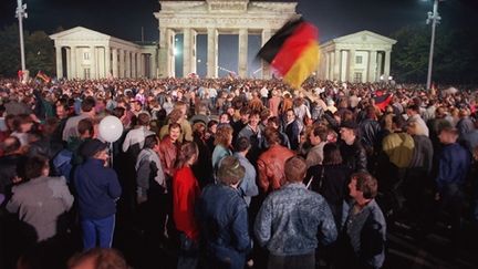 Des jeunes Allemands célèbrent la réunification du pays, le 3 octobre 1990, à la porte de Brandebourg à Berlin (AFP - GILLES LEIMDORFER)