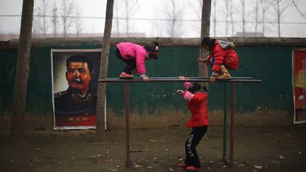 Des enfants jouent dans la cour d'une &eacute;cole &eacute;l&eacute;mentaire o&ugrave; tr&ocirc;ne un portrait de Joseph Staline &agrave; Sitong (Chine), le 3 d&eacute;cem re 2013. (CARLOS BARRIA / REUTERS)