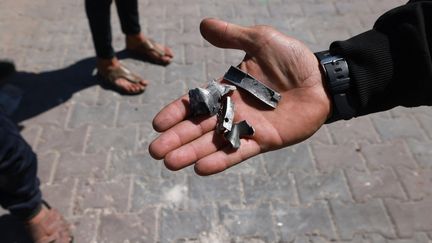 A man shows pieces of metal near a warehouse of the UN agency for Palestinian refugees (UNRWA) in Rafah, March 13, 2024. (MOHAMMED ABED / AFP)