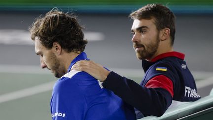 Arthur Rinderknech (à gauche) consolé par Benjamin Bonzi après la défaite en Coupe Davis de l'équipe de France contre l'Australie, à Hambourg (Allemagne), le 15 septembre 2022. (FRANK MOLTER / DPA via AFP)