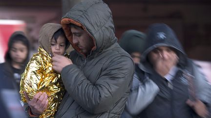 Un Syrien tient son enfant dans les bras, alors que le campement de migrants de la porte de Saint-Ouen&nbsp;(Paris) est &eacute;vacu&eacute;, le 2 octobre 2015. (JOEL SAGET / AFP)