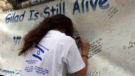 Une jeune Israélienne affiche son soutien au soldat Shalit, à Jérusalem, devant l'habitat de Benjamin Netanyahu. (GALI TIBBON / AFP)