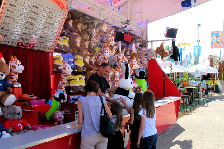 Xaiver Saguet, forain, donne son lot &agrave; une petite fille &agrave; la F&ecirc;te des Loges, le 9 juillet 2015. (CAMILLE ADAOUST / FRANCETV INFO)