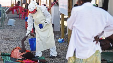 Un membre du personnel m&eacute;dical contr&ocirc;le l'&eacute;tat d'un patient atteint par le virus Ebola dans un centre de la Croix-Rouge &agrave; Kenema (Sierra Leone), le 15 novembre 2014. (FRANCISCO LEONG / AFP)