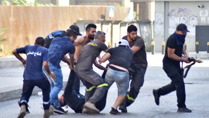 Des hommes emportent le corps d'un de leurs camarades après l'échange de coups de feu qui ont eu lieu à Tayouné, dans la banlieue sud de Beyrouth (Liban), lors d'une manifestation organisée par les mouvements chiites Hezbollah et Amal, le 14 octobre 2021. (- / AFP)