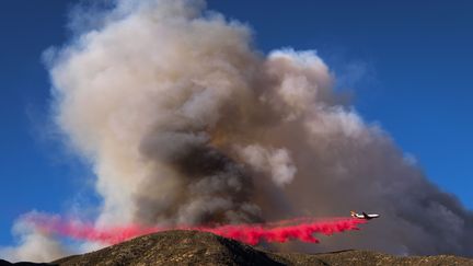 Un avion largue&nbsp;un liquide ignifuge&nbsp;à&nbsp;Lytle Creek (Californie) pour limiter la propagation de l'incendie Blue Cut, en 16 août 2016.&nbsp; (RINGO CHIU / AFP)