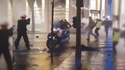 Un policier sort son arme sur les Champs-Elysées, à Paris, le 22 décembre 2018. (FRANCE 2)