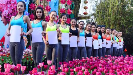 De jeunes Chinoises posent avec une feuille de format A4 pour montrer la finesse de leur taille à Hangzhou, en Chine, le 16 mars 2016. (WEI WEI / IMAGINECHINA / AFP)