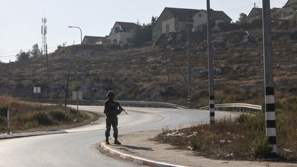 Un soldat israélien monte la garde près de l'entrée d'une colonie israélienne en Cisjordanie occupée, le 22 août 2023. (HAZEM BADER / AFP)