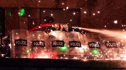 Des policiers visés par des tirs de feux d'artifice utilisent un canon à eau contre des manifestants à Tbilissi, en Géorgie, le 3 décembre 2024. (GIORGI ARJEVANIDZE / AFP)