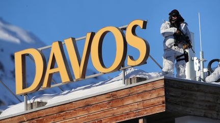 Un policier se tient sur le bâtiment qui accueille le Forum économique mondial de Davos en Suisse, le 20 janvier 2020. (DENIS BALIBOUSE / REUTERS)