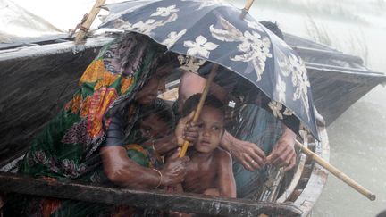 Une famille tente de se prot&eacute;ger de la pluie diluvienne qui s'abat sur Kurigram (Bangladesh), le 3 juillet 2012. (ANDREW BIRAJ / REUTERS)