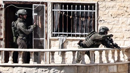 Des soldats de l'armée israélienne prennent position sur le balcon d'un bâtiment, à Qabatiyah, au sud de Jénine, en Cisjordanie occupée, le 19 septembre 2024. (ZAIN JAAFAR / AFP)