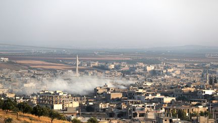 Un panache de fumée au-dessus de la ville syrienne de Kahn Cheikoun (Syrie), le 5 août 2019.&nbsp; (OMAR HAJ KADOUR / AFP)