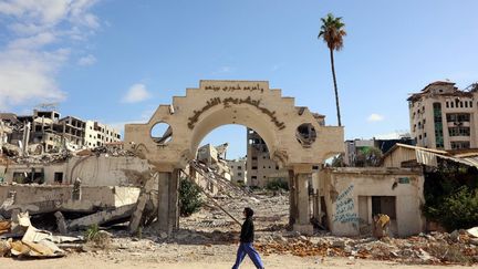 Une personne passe devant les ruines d'un batiment administratif détruit, à Gaza, le 22 septembre 2024. (OMAR AL-QATTAA / AFP)