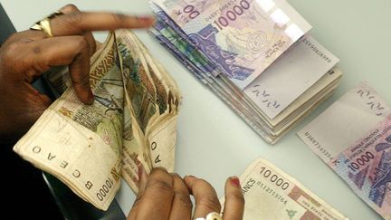 Des billets de 10 000 Francs CFA dans une banque sénégalaise à Dakar, le 15 septembre 2004 (photo d’illustration). (NIC BOTHMA / EPA)