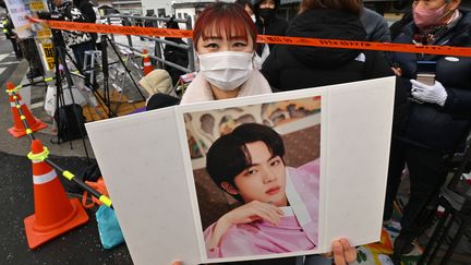 Un fan tient une photo du chanteur Jin du groupe coréen BTS, devant une unité d'entraînement militaire à Yeoncheon le 13 décembre 2022. C'est l'endroit où le chanteur doit arriver pour commencer son service militaire (JUNG YEON-JE / AFP)