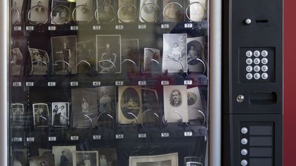 Aujourd'hui, dans les brocantes et vide-greniers, n'importe qui peut acheter les photos des ancêtres de quelqu'un d'autre, qui deviennent un produit de consommation comme un autre, comme une barre chocolatée ou une bouteille d'eau. Audrey Laurens s'est amusée à inventer un "distributeur d'ancêtres photographiques", comme un distributeur de sucreries, qui permet à chacun de se composer une famille imaginaire.
 (Audrey Laurans)