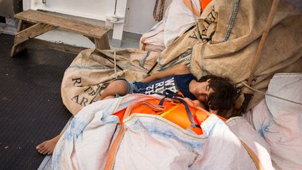 Un jeune homme dort sur le pont de l'Aquarius, balancé par la houle. (MAUD VEITH / SOS MEDITERRANEE)