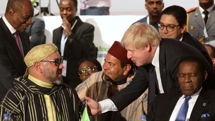 Le ministre britannique des Affaires étrangères Boris Johnson, en conversation avec le roi du Maroc Mohamed VI, au Sommet UE-Afrique d'Abidjan, le 29 novembre 2017. (LUDOVIC MARIN / POOL / AFP)