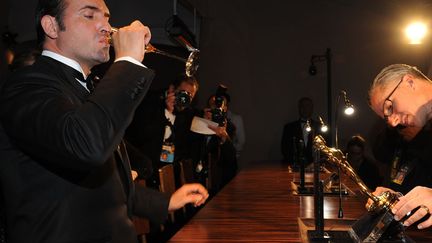 DO : s'enfiler une coupe de champagne devant sa statuette du meilleur acteur. L'air de rien. (VALERIE MACON / AFP)