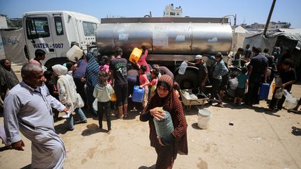 Des Palestiniens font la queue pour remplir leurs récipients d'eau, dans le camp de Deir el-Balah, dans le centre de la bande de Gaza, le 12 juin 2024. (MAJDI FATHI / NURPHOTO / AFP)