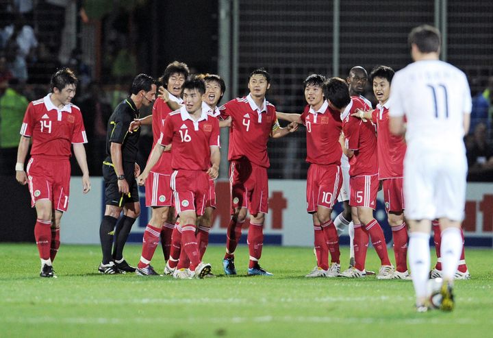 Les joueurs chinois célèbrent leur ouverture du score face à un André-Pierre Gignac dépité, le 4 juin 2010, à Saint-Pierre de la Réunion. (FRANCK FIFE / AFP)