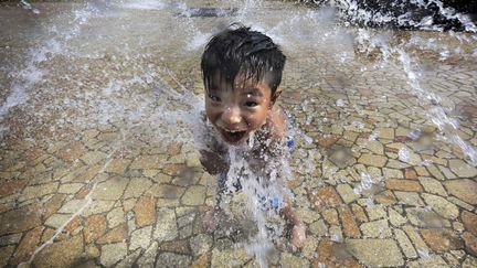 Un gar&ccedil;on joue dans une fontaine &agrave; Tokyo (Japon), le 6 juillet 2013. (ITSUO INOUYE / AP / SIPA)