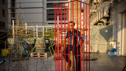 L'artiste Hongkongais Kacey Wong joue l'hymne national chinois à l'accordéon, enfermé dans une cage métallique rouge. Il s'agit de sa performance intitulée "The Patriot", le 6 décembre 2018 (ANTHONY WALLACE / AFP)