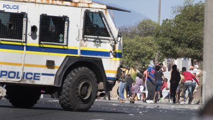 Des habitants&nbsp;du township de Mitchells Plain, près du Cap, s'enfuient à l'arrivée d'un véhicule de police pendant des heurts avec les forces de l'ordre le 14 avril 2020. (RODGER BOSCH / AFP)