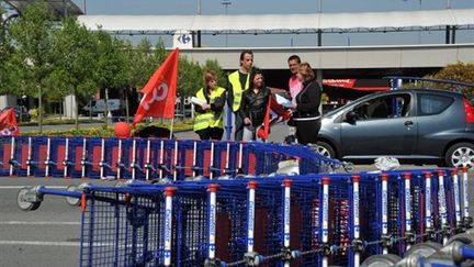 Employés de Carrefour derrière des barrages de caddies renversés, devant le magasin de Lomme (Nord), le 9 avril 2011 (AFP / Philippe Huguen)