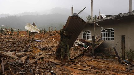 Un soldat d&eacute;blaye le terrain, le 19 septembre 2013, dans le village de La Pintada (sud du Mexique). Celui-ci a &eacute;t&eacute; emport&eacute; par une coul&eacute;e de boue en raison des temp&ecirc;tes qui frappent le pays.&nbsp; (TOMAS BRAVO / REUTERS)