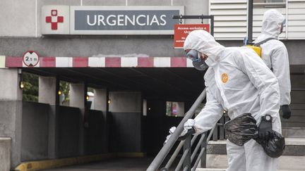 Des militaires espagnols désinfectent les escaliers devant les urgences d'un hôpital à Gijon, le 18 mars 2020. (ALVARO FUENTE / NURPHOTO / AFP)