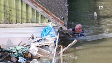 Un habitant de la région inondée de Kherson tente de sauver ce qu'il peut de sa maison, le 7 juin 2023. (OLEXANDER KORNYAKOV / AFP)