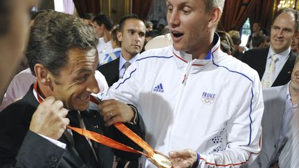 Champions olympiques &agrave; P&eacute;kin, les handballeurs fran&ccedil;ais sont re&ccedil;us, le 26 ao&ucirc;t 2008, par Nicolas Sarkozy. Le pivot Christophe Kempe s'occupe de l'essayage des m&eacute;dailles. (  REUTERS)