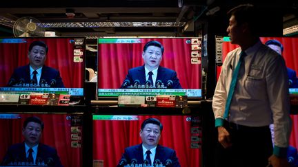 Un employé d'une boutique de multimédia regarde le discours d'ouverture du président de la République populaire de Chine, Xi Jinping, le 18 octobre 2017, à Hong-Kong. (Photo d'illustration) (ANTHONY WALLACE / AFP)